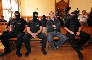 Budapest, 2009. szeptember 16. A három hónapja terrorcselekményekkel és országgyûlési képviselõk elleni támadásokkal meggyanúsított, és elõzetes letartóztatásban lévõ Budaházy György kommandósok között ülve hallgatja az ítélet indoklását. Egy év - három évre felfüggesztett - börtönbüntetésre ítélte az alkotmányos rend erõszakos megváltoztatásának elõkészülete miatt Budaházy Györgyöt a Fõvárosi Bíróság elsõ fokon. Korábban ebben az ügyben elsõ fokon felmentették a vádlottat, ám a Fõvárosi Ítélõtábla azt a döntést hatályon kívül helyezte és új elsõfokú eljárásra utasított. MTI Fotó: Kovács Tamás